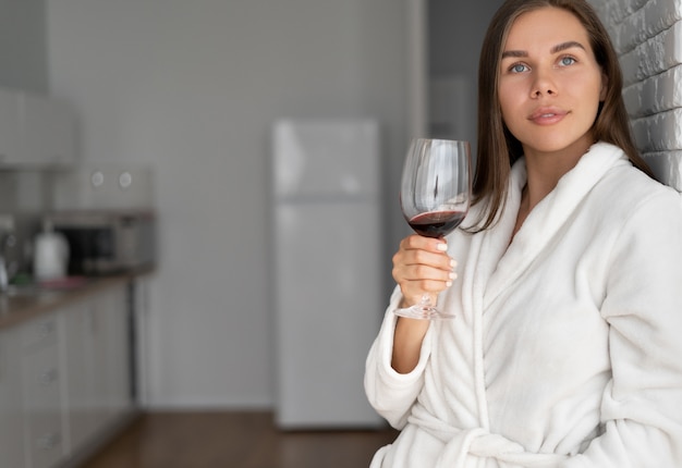 Belle jeune femme avec un verre de vin dans une chambre d'hôtel.