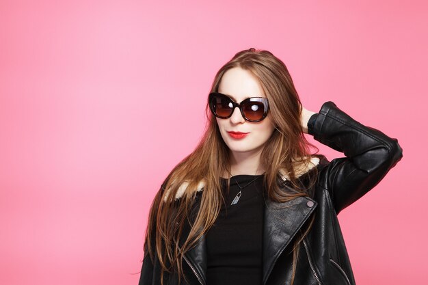 Belle jeune femme en veste de cuir et lunettes