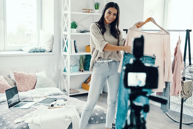 Belle jeune femme en vêtements décontractés faisant une vidéo sur les réseaux sociaux tout en passant du temps à la maison