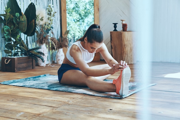 Belle jeune femme en vêtements de sport qui s'étend sur le patio