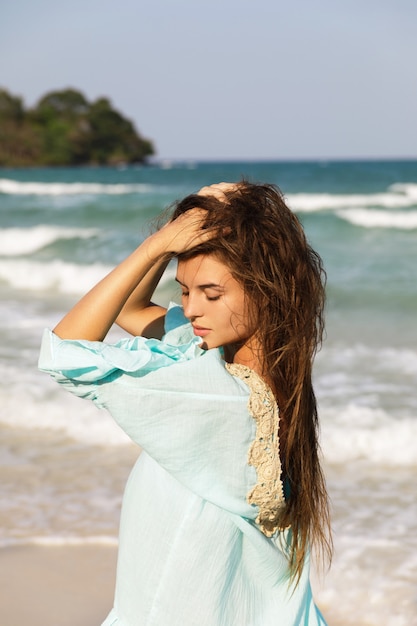 Belle jeune femme vêtue d'une belle robe bleue se promène au bord de la mer