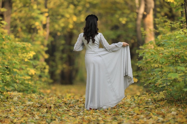 belle jeune femme vêtue d'une robe blanche dans la forêt d'automne