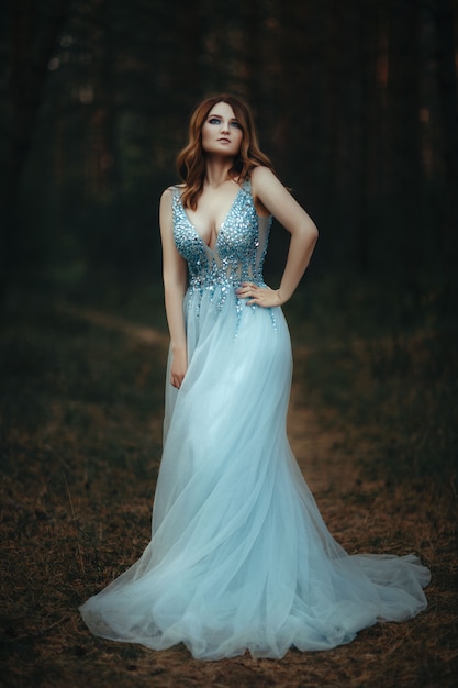 Belle jeune femme vêtue d'une robe blanche dans la forêt