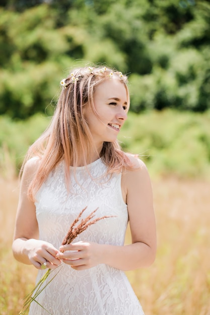 Belle jeune femme vêtue d'une robe en dentelle vintage blanche sur le pré