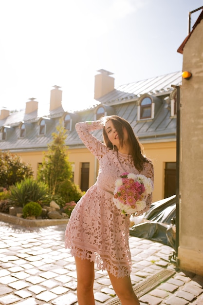 Belle jeune femme vêtue d'une robe rose en dentelle, posant dans des rayons de lumière le matin