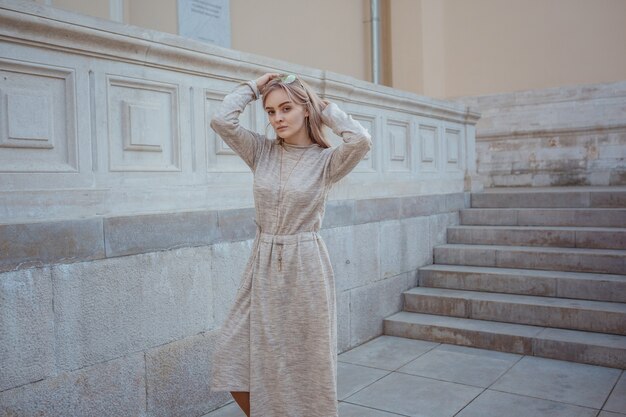 Belle jeune femme vêtue d'une robe tricotée beige se promène dans les rues de Moscou, par temps de printemps ensoleillé