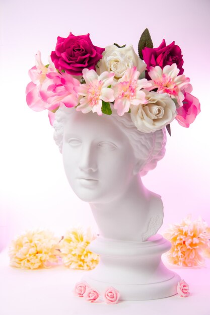 Belle jeune femme visage blanc et fleurs colorées. Buste antique en plâtre de Vénus dans une couronne de fleurs. Fille modèle printemps et été de beauté avec bouquet frais.