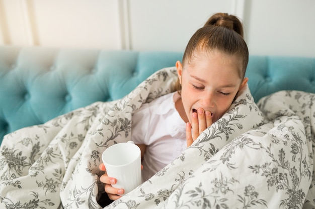 belle jeune fille adolescente dans une couverture avec une tasse