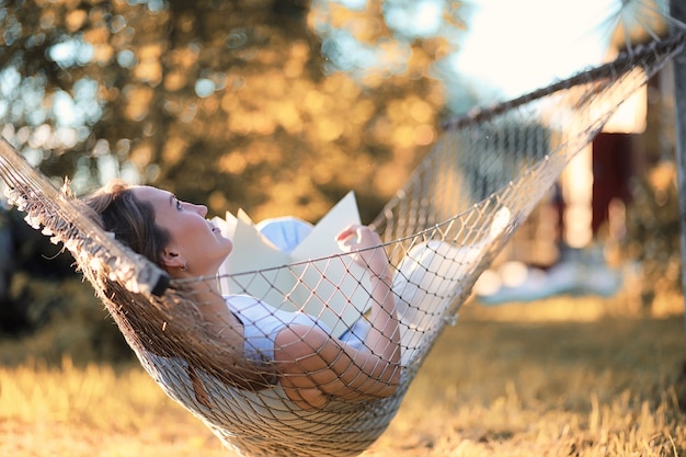 Belle jeune fille allongée et lisant un livre à l'automne en plein air