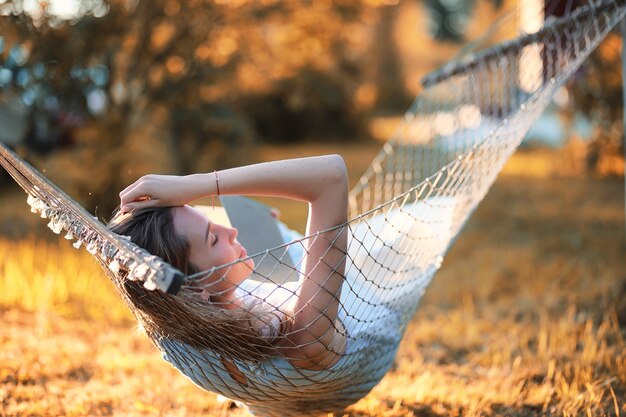 Belle jeune fille allongée et lisant un livre à l'automne en plein air