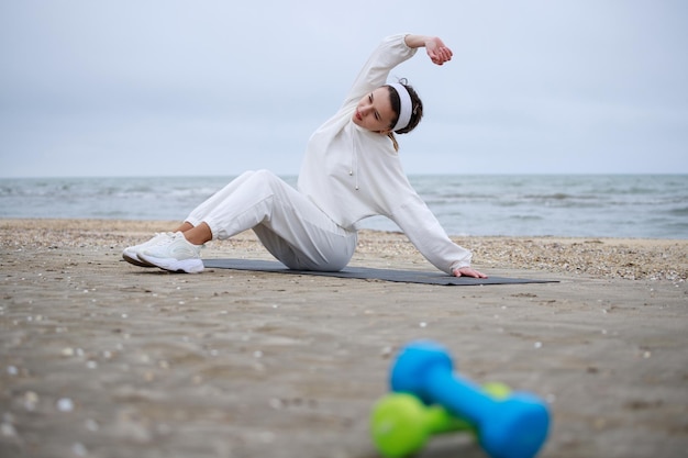 La belle jeune fille allongée sur le tapis de yoga et étirant son corps Photo de haute qualité