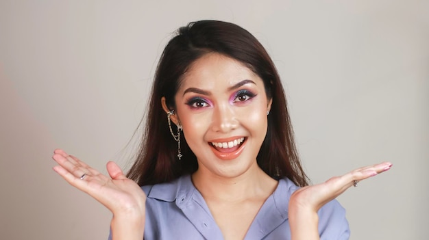 Une belle jeune fille asiatique avec un maquillage coloré sur fond blanc regarde dans le cadre