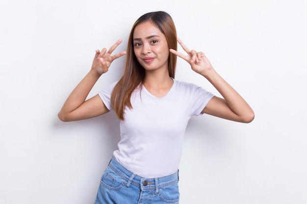 belle jeune fille asiatique montrant le geste de la main de la paix ou de la victoire sur fond blanc