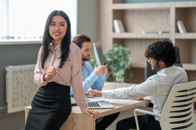 Belle jeune fille asiatique travaillant avec des collègues au bureau