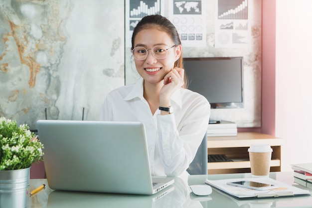 Belle jeune fille asiatique travaillant dans un bureau à domicile avec un ordinateur portable