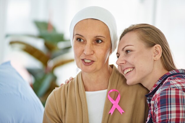 Belle jeune fille assise à côté de sa mère qui lutte contre le cancer pour la soutenir sur son lit d'hôpital