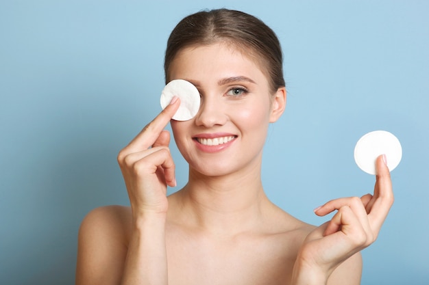 Belle jeune fille au maquillage nude enlève le maquillage avec un coton