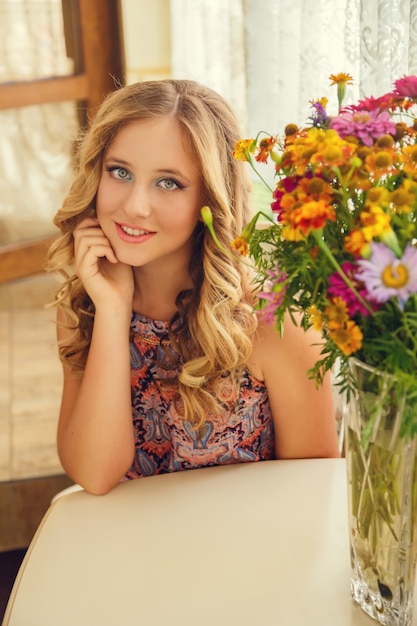 Une belle jeune fille aux cheveux blonds assis à la table
