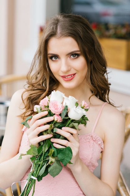 Belle jeune fille aux cheveux bruns avec un bouquet de roses, maquillage professionnel et style.