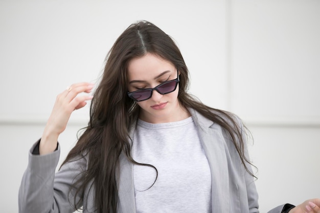 Belle jeune fille aux cheveux longs en lunettes de soleilPortrait d'une femme dans la rue