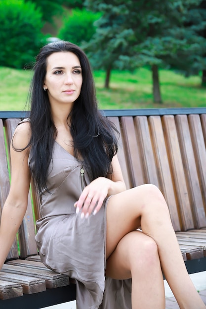 Belle, jeune fille aux cheveux noirs dans une robe d'été assise sur un banc