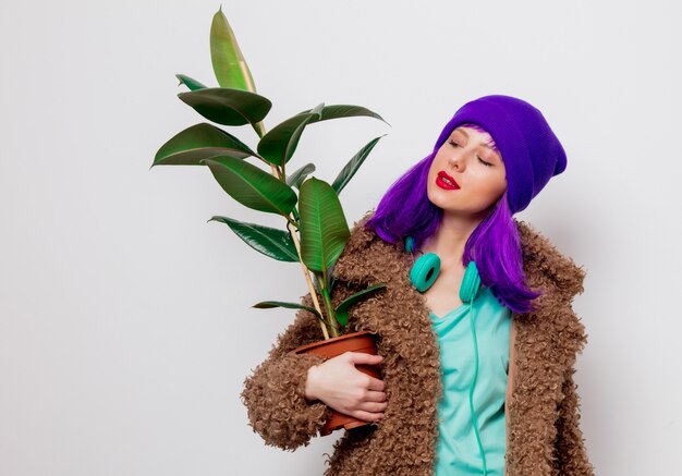 Belle jeune fille aux cheveux pourpres en veste avec plante