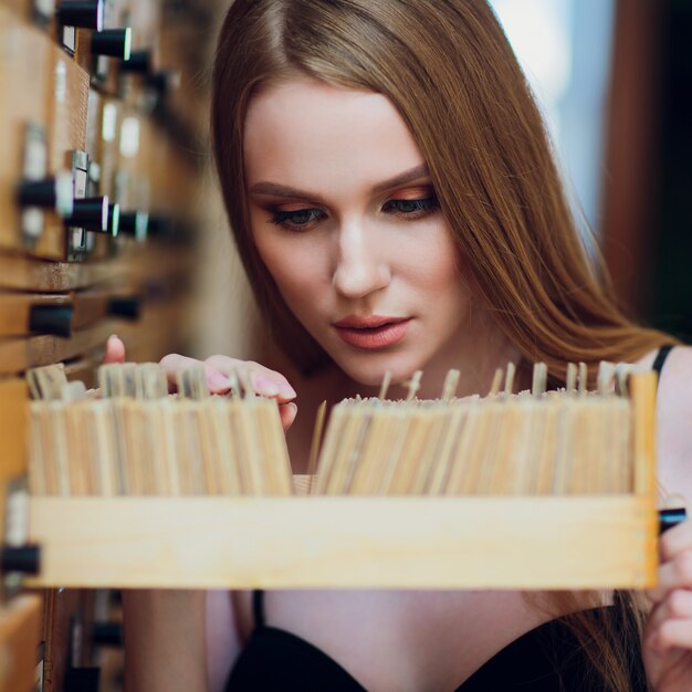 Belle jeune fille aux cheveux raides foncés ouvre la boîte et recherche des données dans le classeur de la bibliothèque