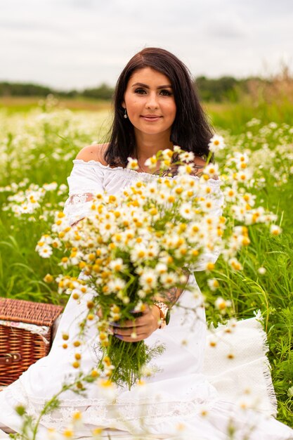 Photo belle jeune fille aux cheveux roux bouclés dans le champ de camomille