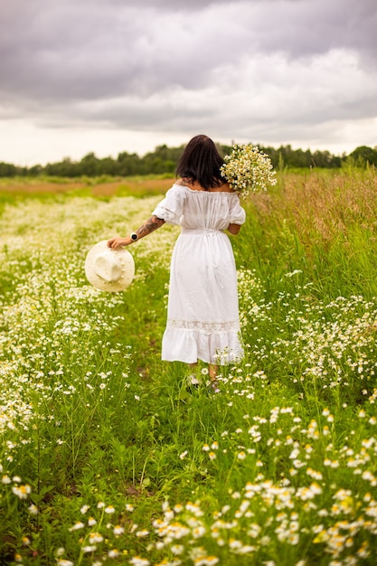 Belle jeune fille aux cheveux roux bouclés dans le champ de camomille