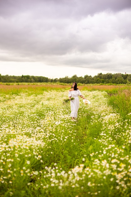 Belle jeune fille aux cheveux roux bouclés dans le champ de camomille