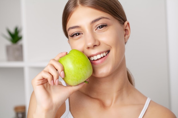 Belle jeune fille aux dents blanches, main dans la main de pomme verte fraîche