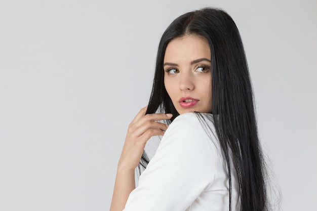 Belle jeune fille aux longs cheveux noirs sur fond blanc isolé