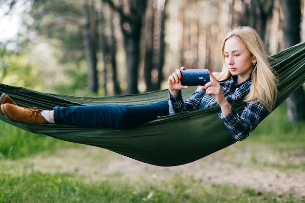 Belle jeune fille blonde dans un hamac en prenant une photo de la nature