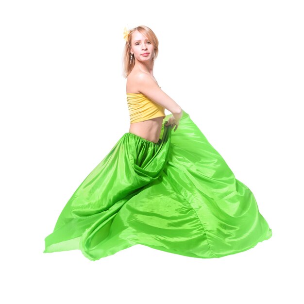 Photo belle jeune fille blonde dans un haut jaune une longue jupe verte et une épingle à cheveux avec une fleur sur la tête dansant