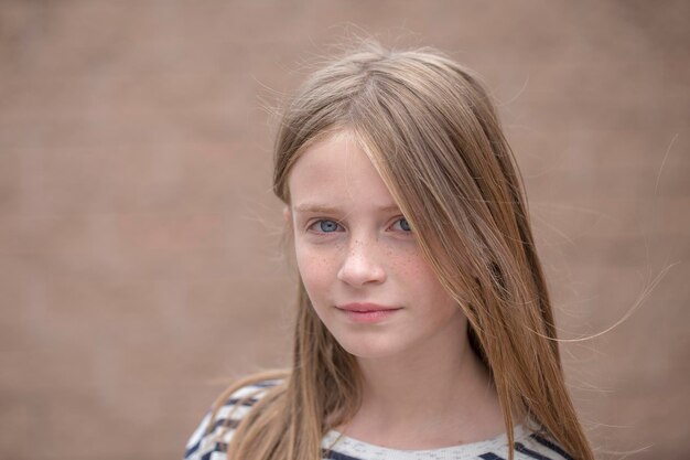 Belle jeune fille blonde avec des taches de rousseur à l'extérieur sur fond de mur close up portrait