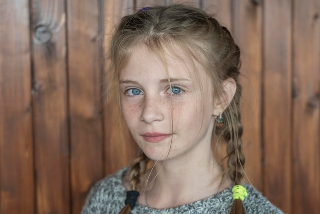 Belle jeune fille blonde avec des taches de rousseur à l'intérieur sur fond de bois closeup portrait