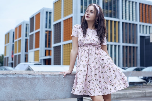 Belle jeune fille brillante dans une robe d'été debout sur un pont