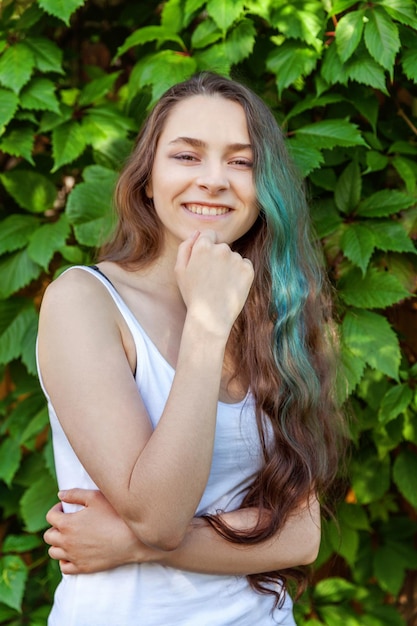 Belle jeune fille brune hipster aux longs cheveux verts souriant sur fond de parc