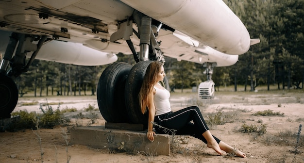 Belle jeune fille brune se dresse sur le fond de l'ancien avion militaire.