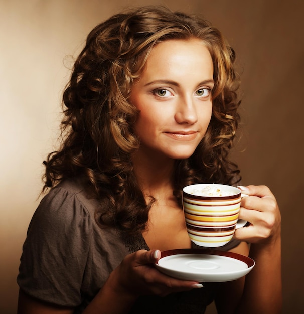 Une belle jeune fille buvant du thé ou du café.