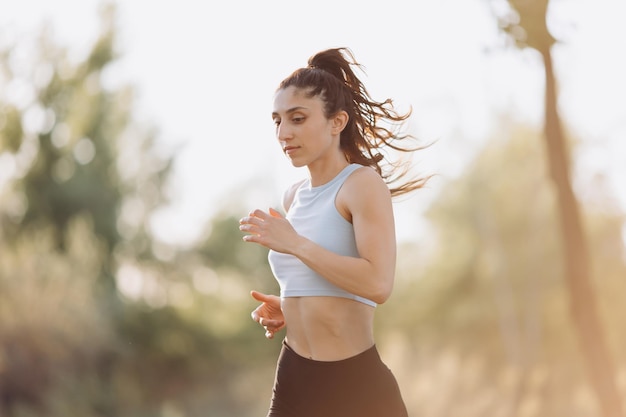 Belle jeune fille court dans le parc dans un tshirt sports running santé