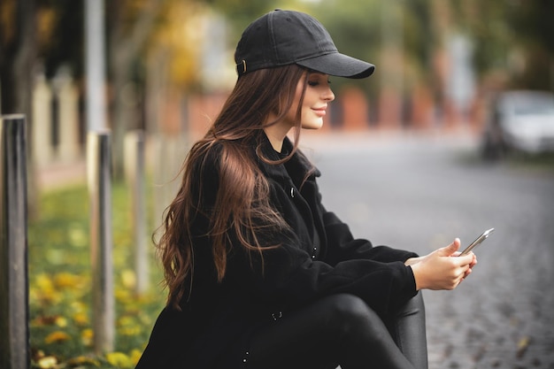 Belle jeune fille dans une casquette de baseball avec un smartphone dans ses mains
