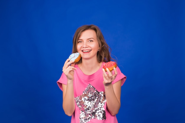 Belle jeune fille drôle avec des beignets sur bleu.