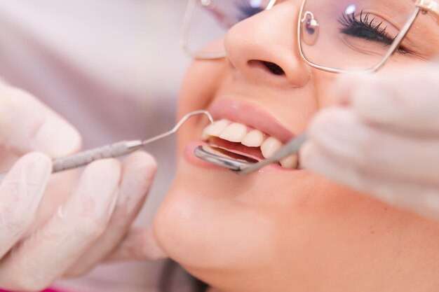 Photo une belle jeune fille est traitée par un dentiste à l'aide d'outils dentaires.