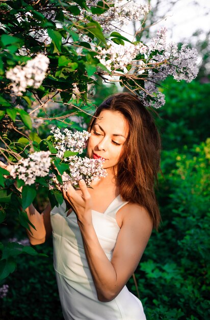 belle jeune fille en été dans le parc au coucher du soleil dans une robe souriante