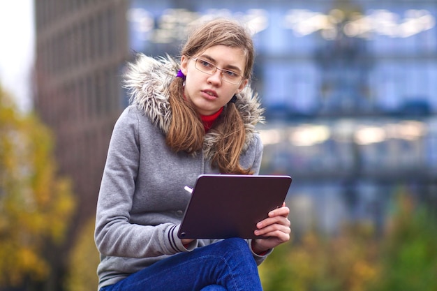 Belle jeune fille étudiante à l'université ou au collège est assise dans le parc