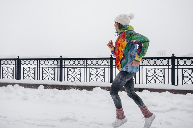 Une belle jeune fille fait du jogging un jour givré et neigeux. Sports, mode de vie sain