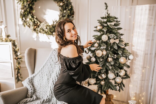 Belle jeune fille heureuse décorer les jouets de Noël de l'arbre du nouvel an