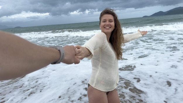 Belle jeune fille heureuse femme positive est en train de mener l'homme tenant la main suivez-la à la plage d'été