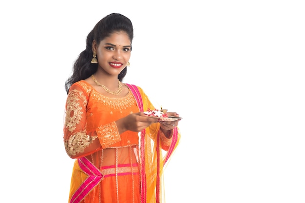 Belle jeune fille indienne tenant pooja thali ou effectuant un culte sur blanc
